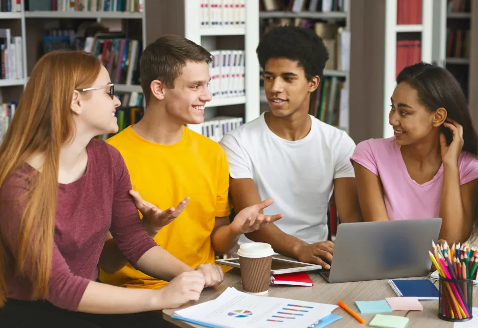 Four students talking at a library table